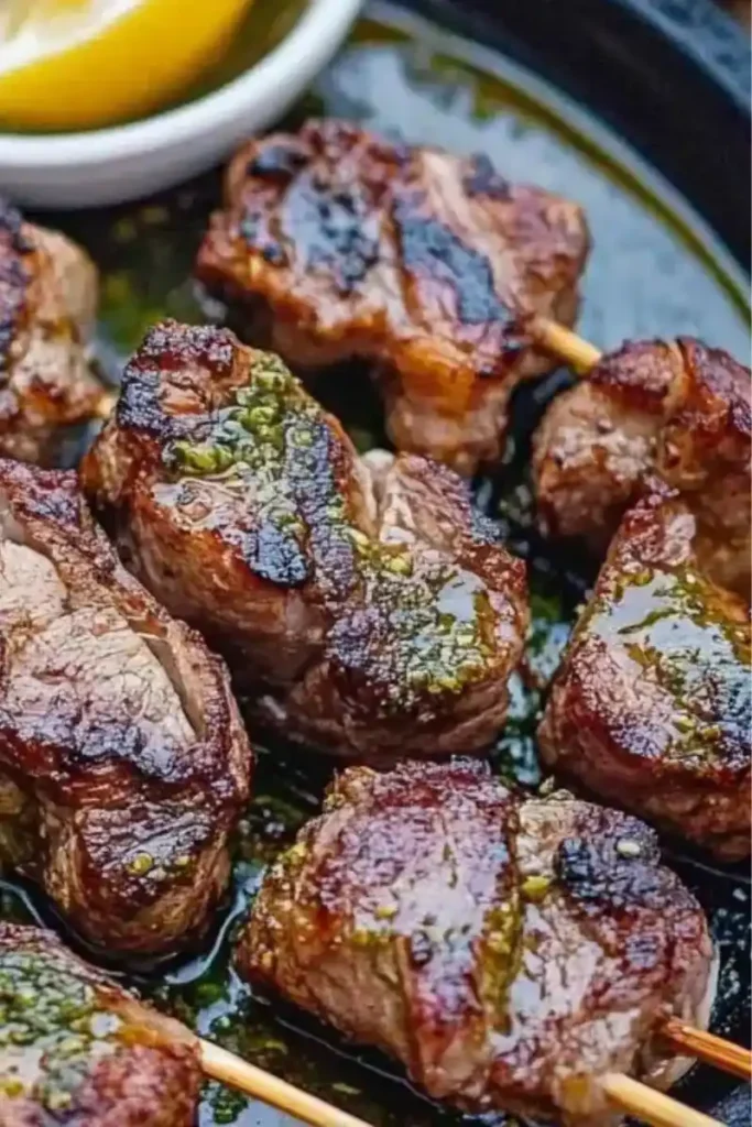 Close-up of grilled lamb chunks on skewers glazed with sauce.