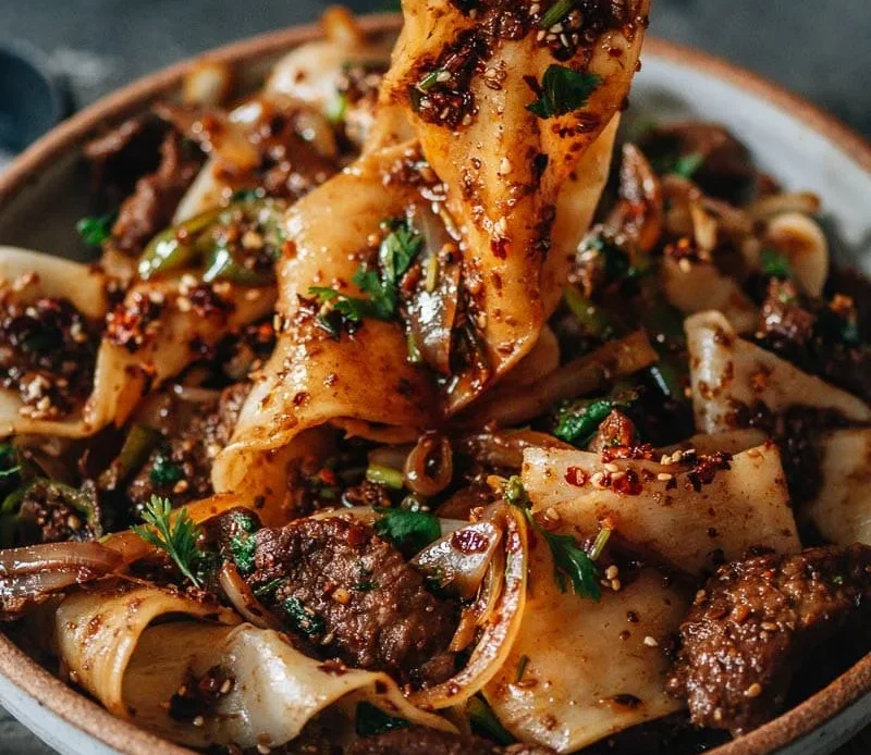 A bowl of hearty chili topped with cheese and herbs, ideal for a cozy meal.